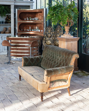 Sofá con respaldo de terciopelo verde y asiento de arpillera con estructura vista de madera